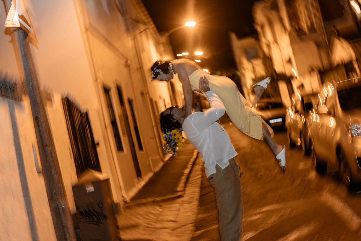 A couple dances intimately in a narrow, warmly-lit European alleyway at night.