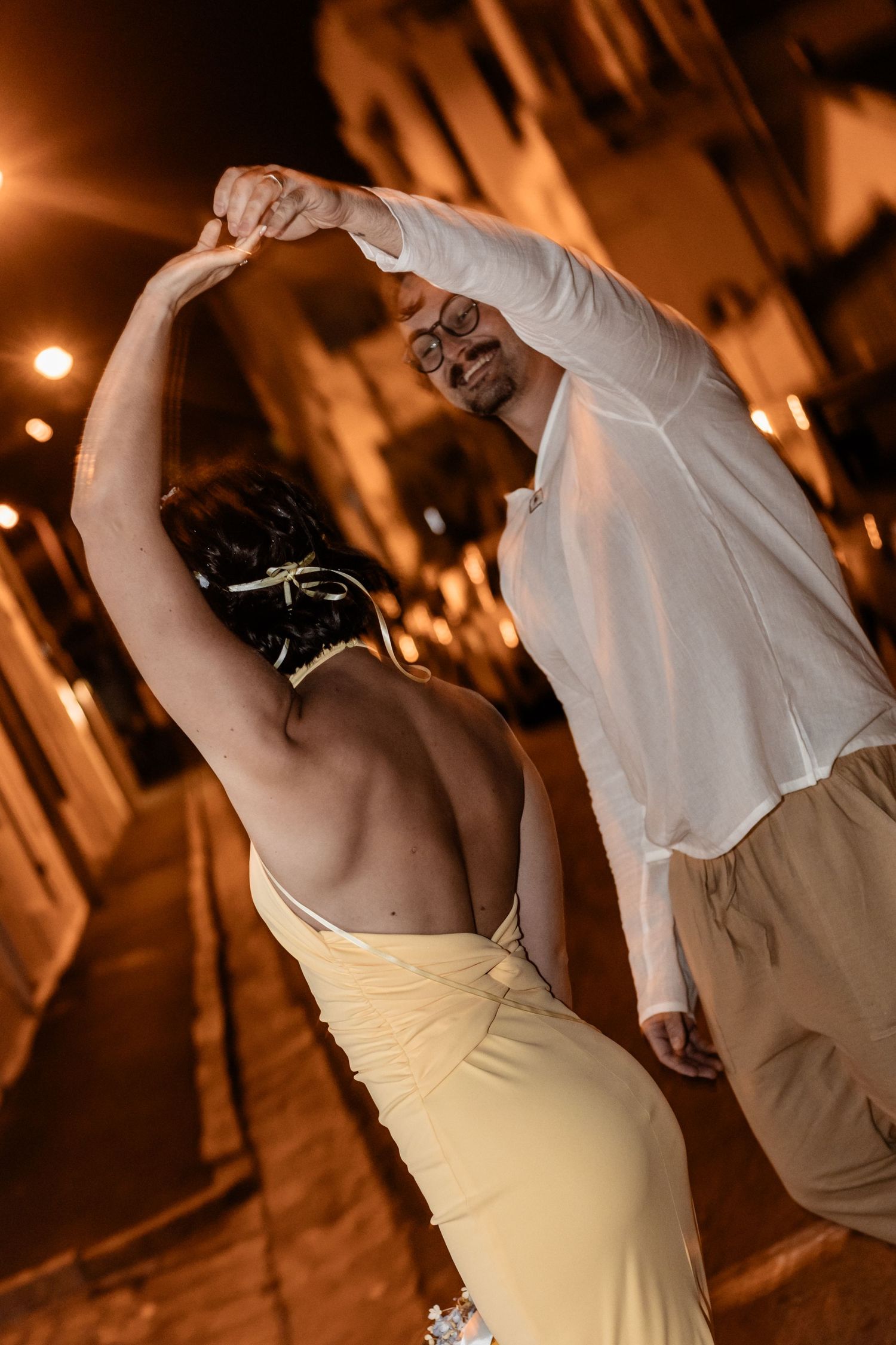A couple performs an elegant dance move under warm lighting at an evening celebration.