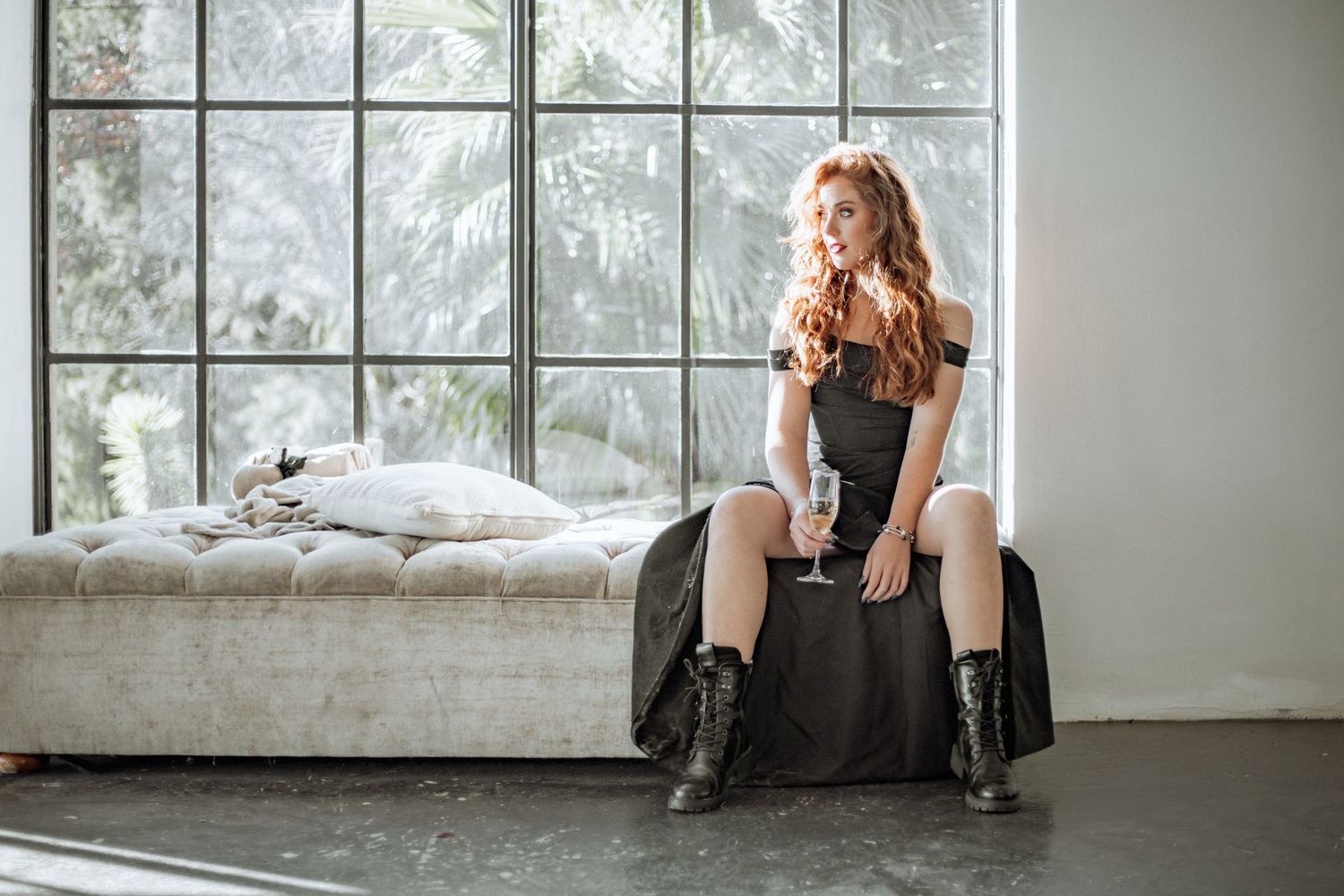 Dramatic black and white photo series showing person in vintage-style dress sitting against industrial windows.