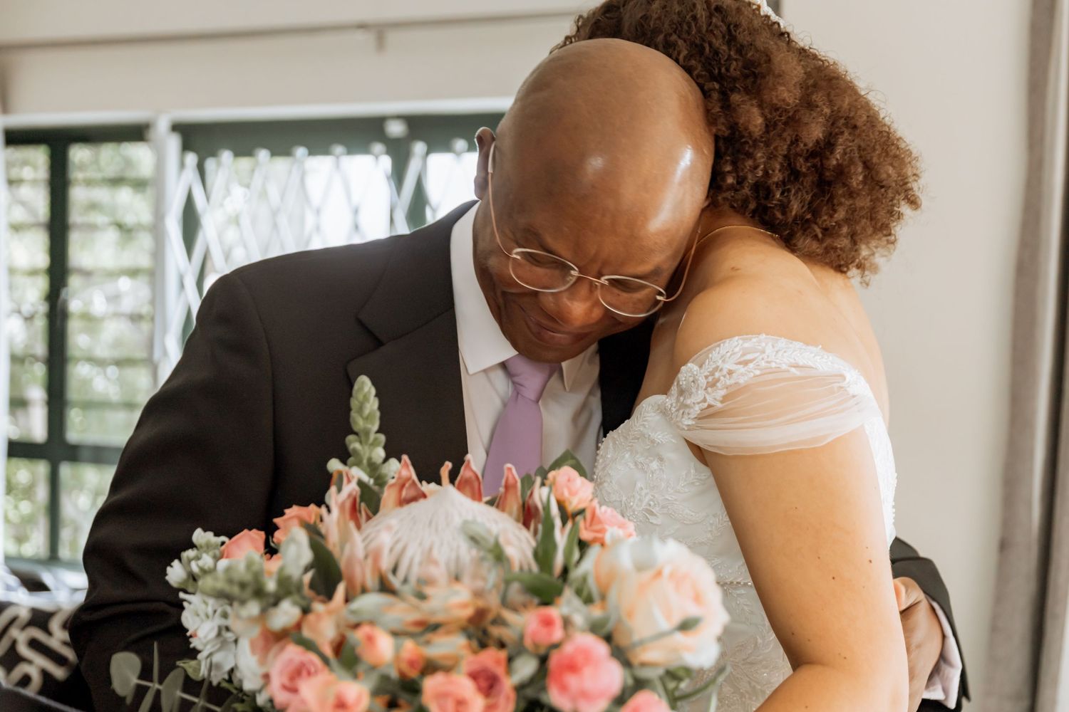 A couple shares an intimate moment in a copper-colored setting with soft lighting and floral accents.
