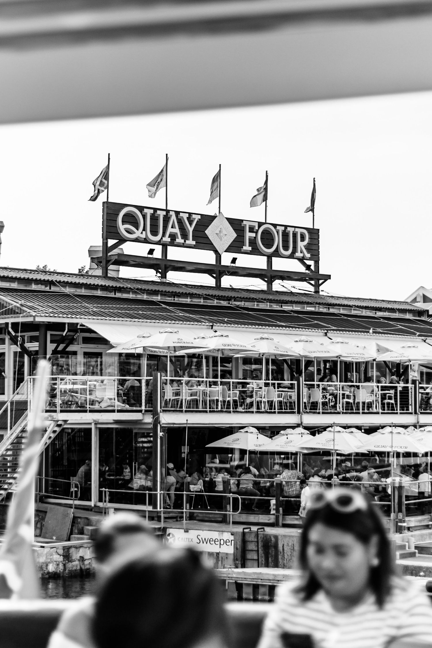 Multiple black and white panoramic views of a waterfront area with Quay signage and buildings visible in the background.
