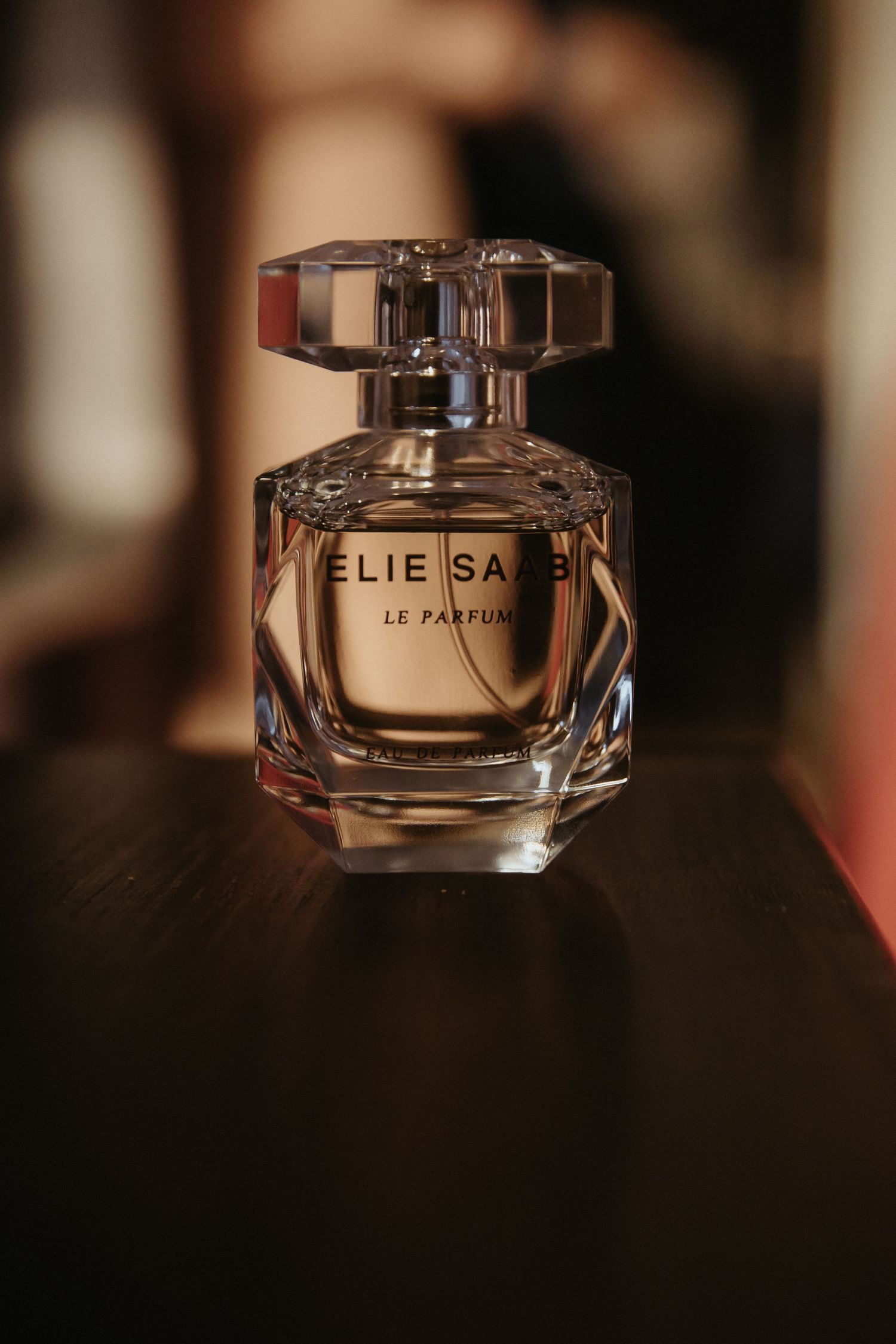 Crystal perfume bottle labeled 'ELIE' photographed from different angles on a dark surface with soft lighting.