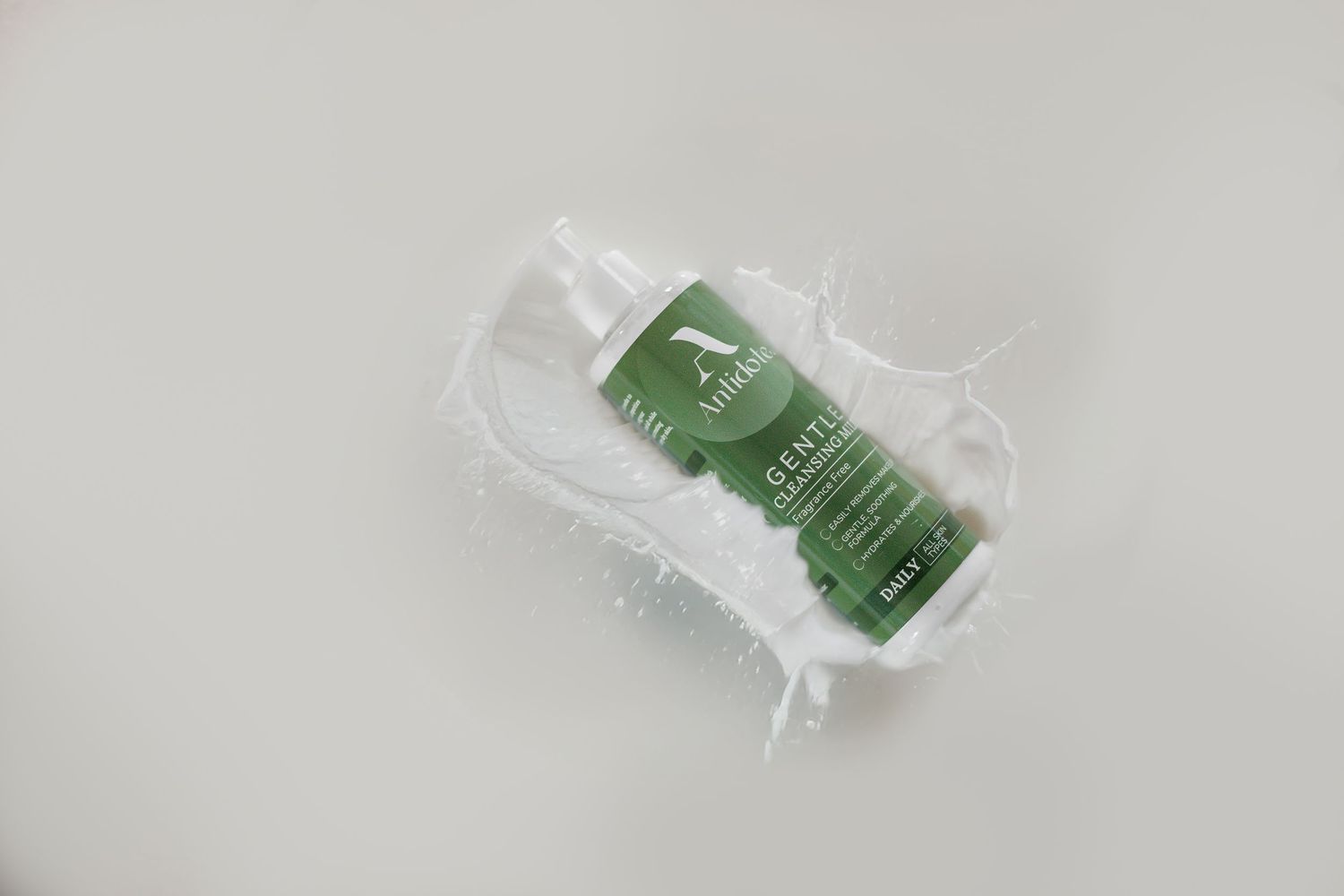 A green tea bag wrapped in clear plastic packaging lies on a white surface.