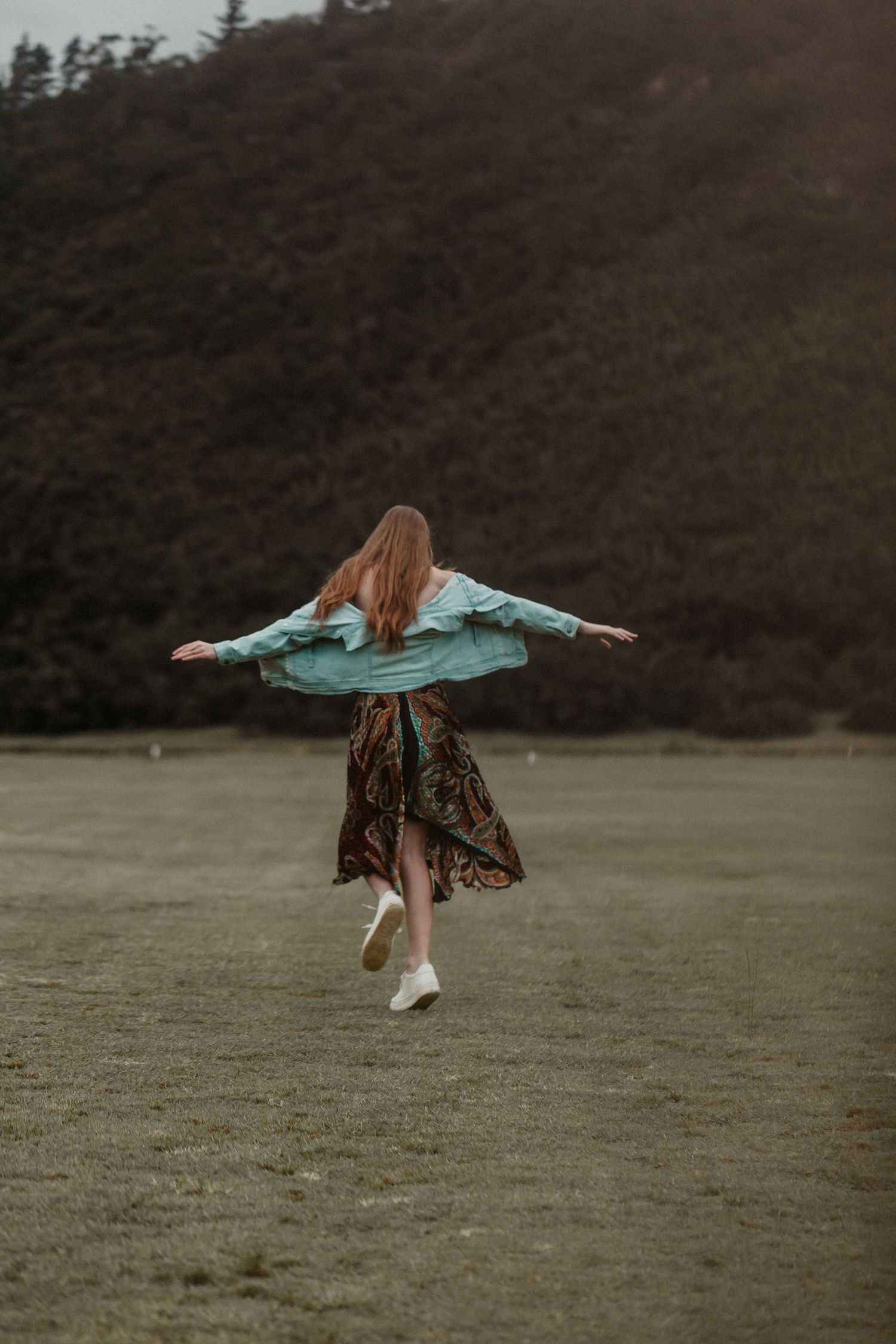 A sequence of images showing a person in a teal jacket spinning and twirling in a misty field.