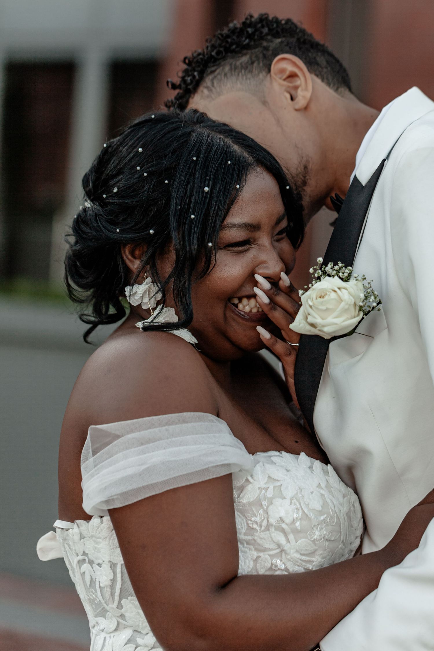 Intimate moment between newlyweds sharing laughter in formal wedding attire.
