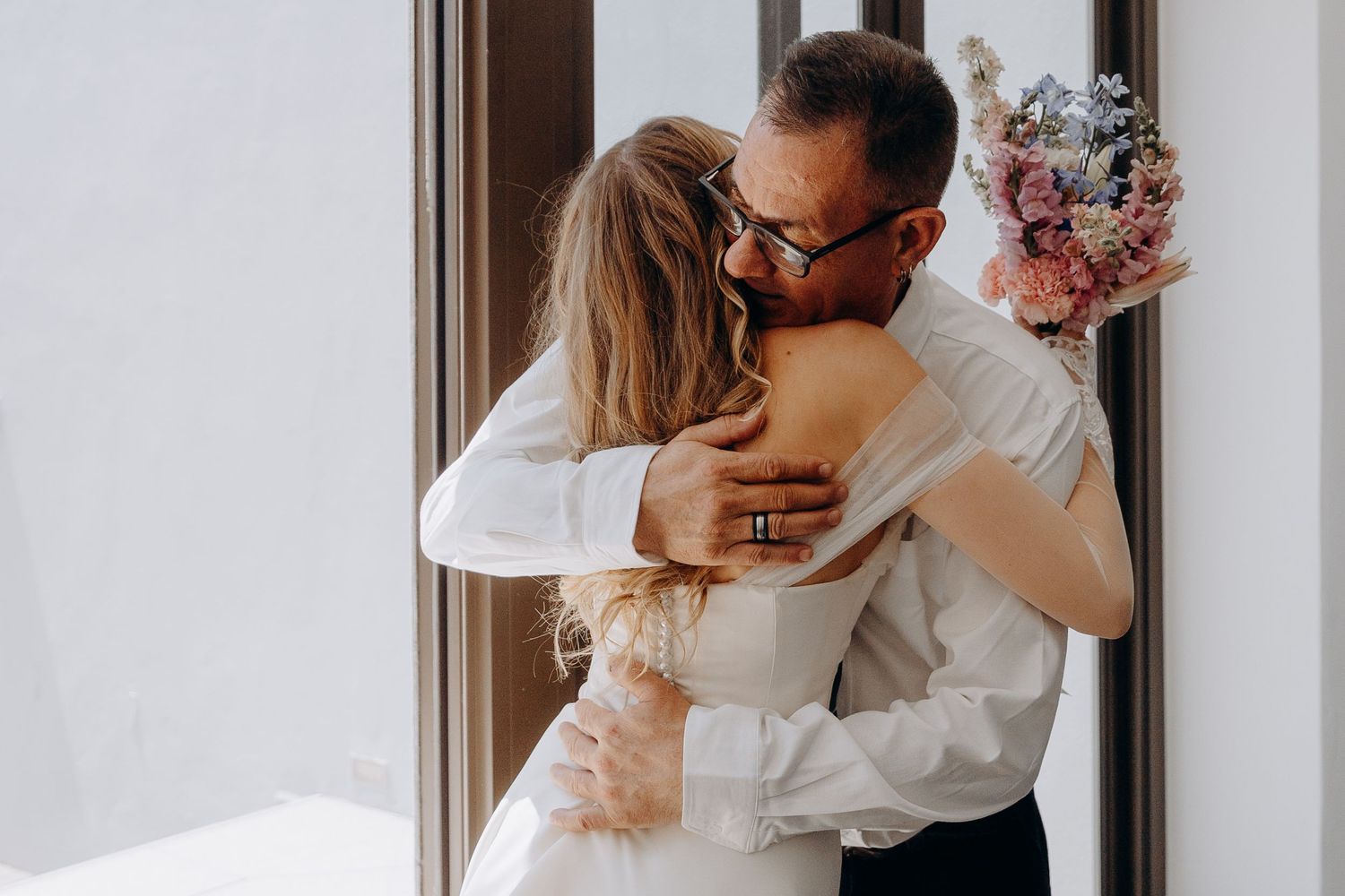 A series of four romantic wedding photos showing a couple embracing and kissing in an intimate indoor setting.