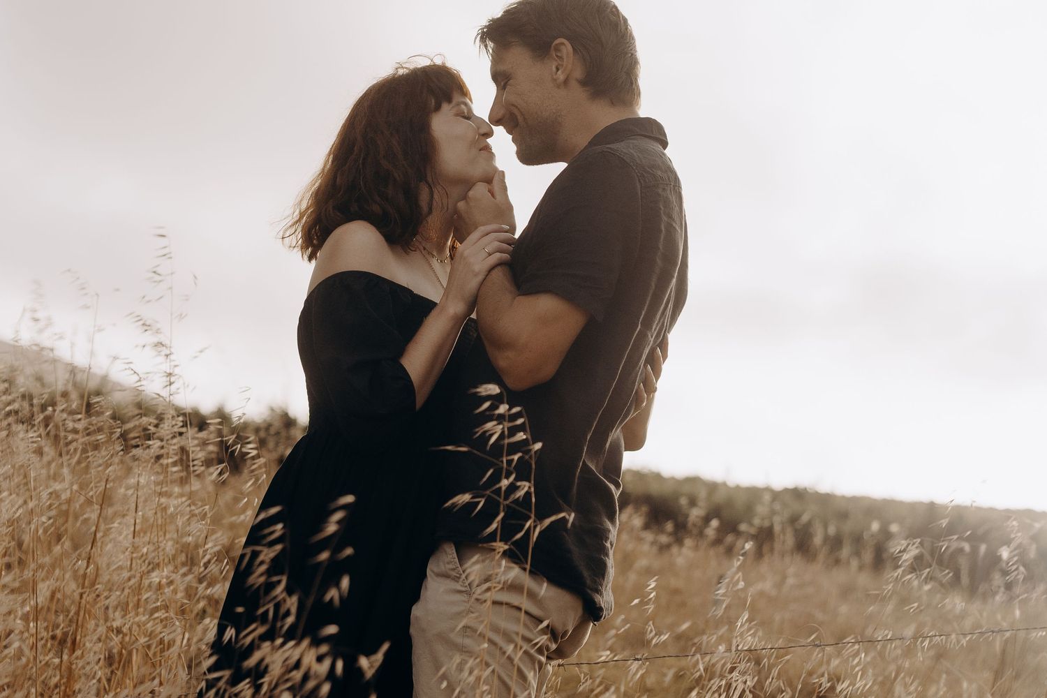 A couple embraces in a romantic moment outdoors with a sepia-toned filter effect.