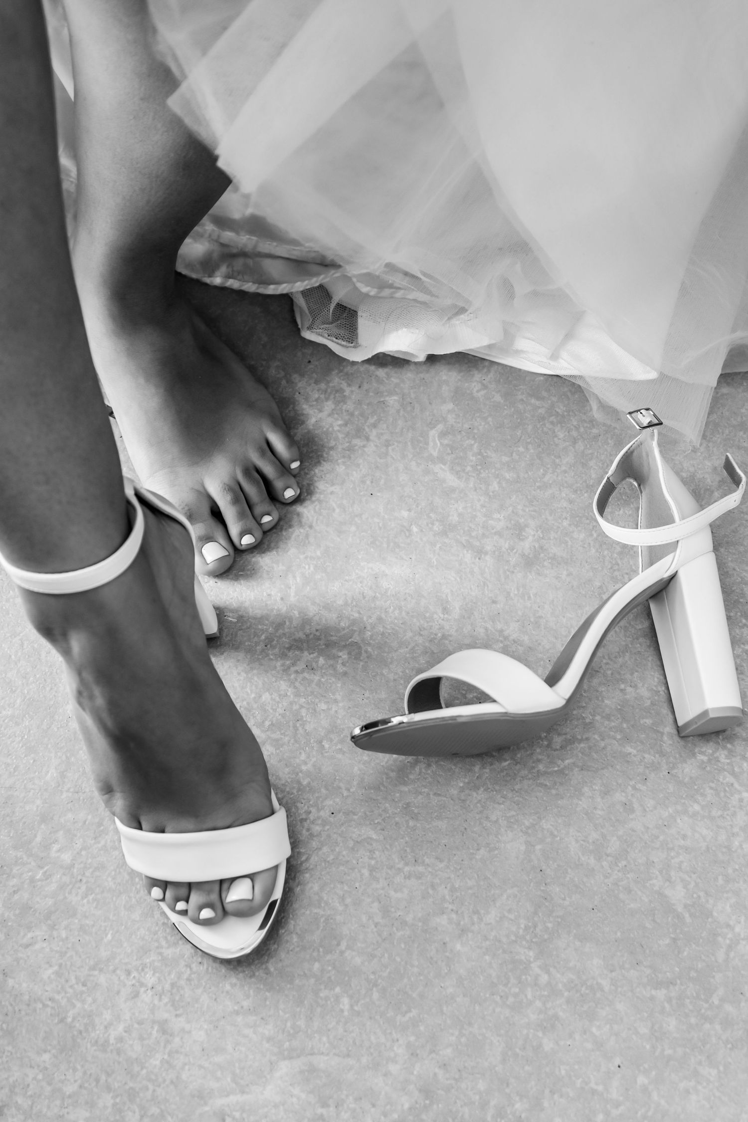 A series of black and white photos showing white bridal shoes and the hem of a wedding dress on a textured floor.