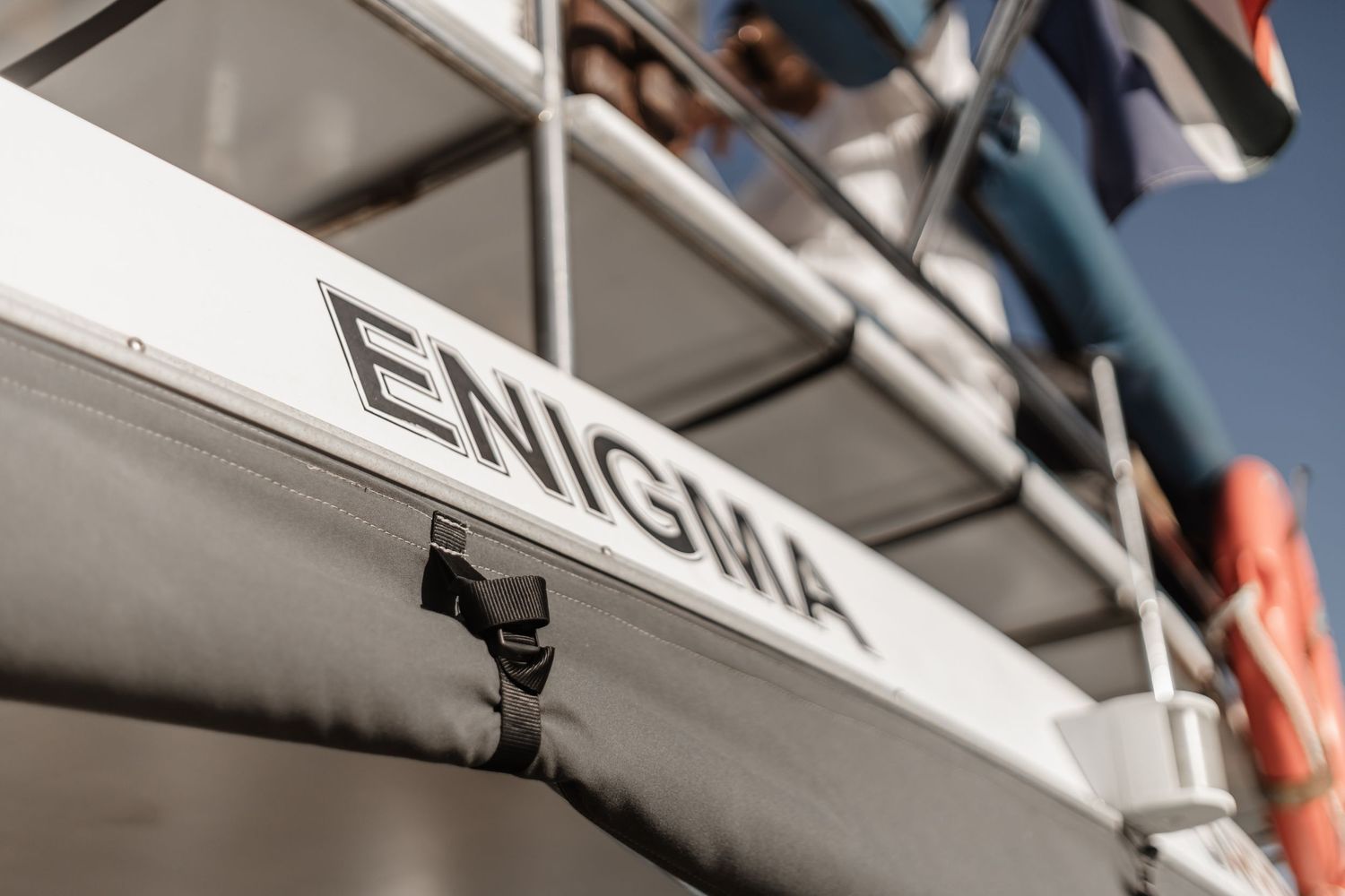 A close-up view of an aircraft tail with the letters 'ENIGMA' visible on its white fuselage against a blue sky.