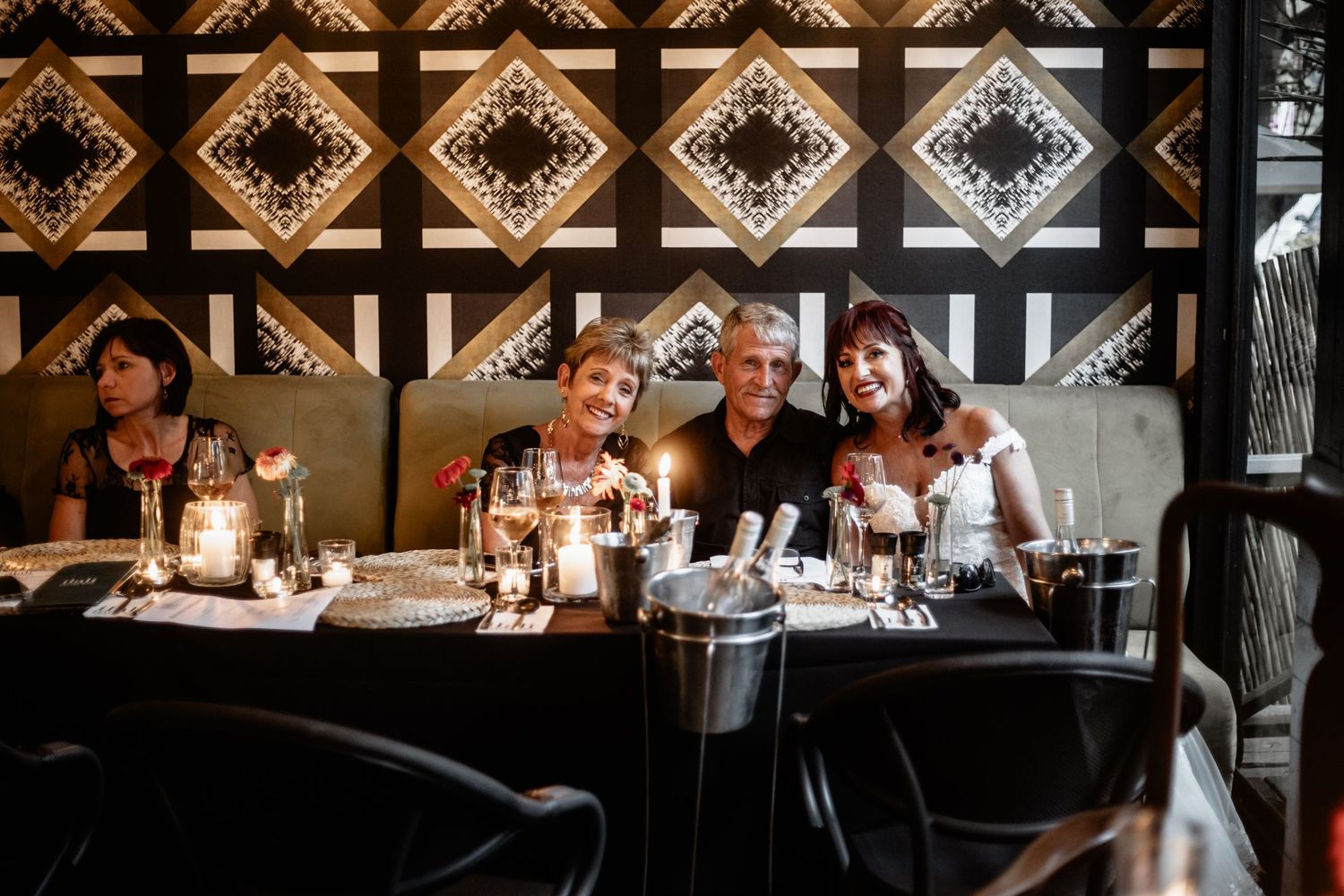 Dinner guests enjoying an intimate meal at a restaurant with ornate geometric ceiling patterns and candlelit ambiance.