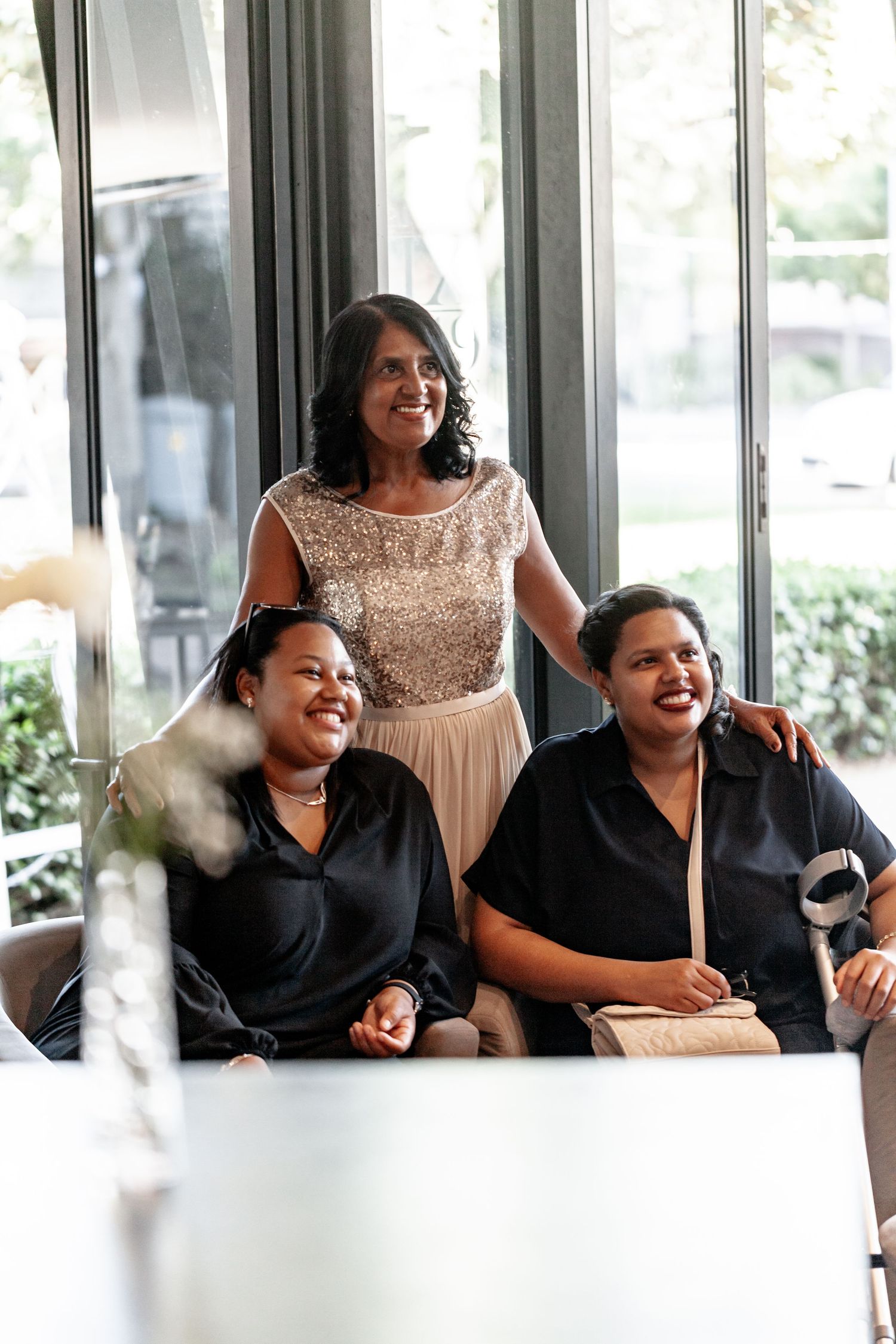 Wedding guests share a joyful moment of laughter while seated together at an indoor reception venue.