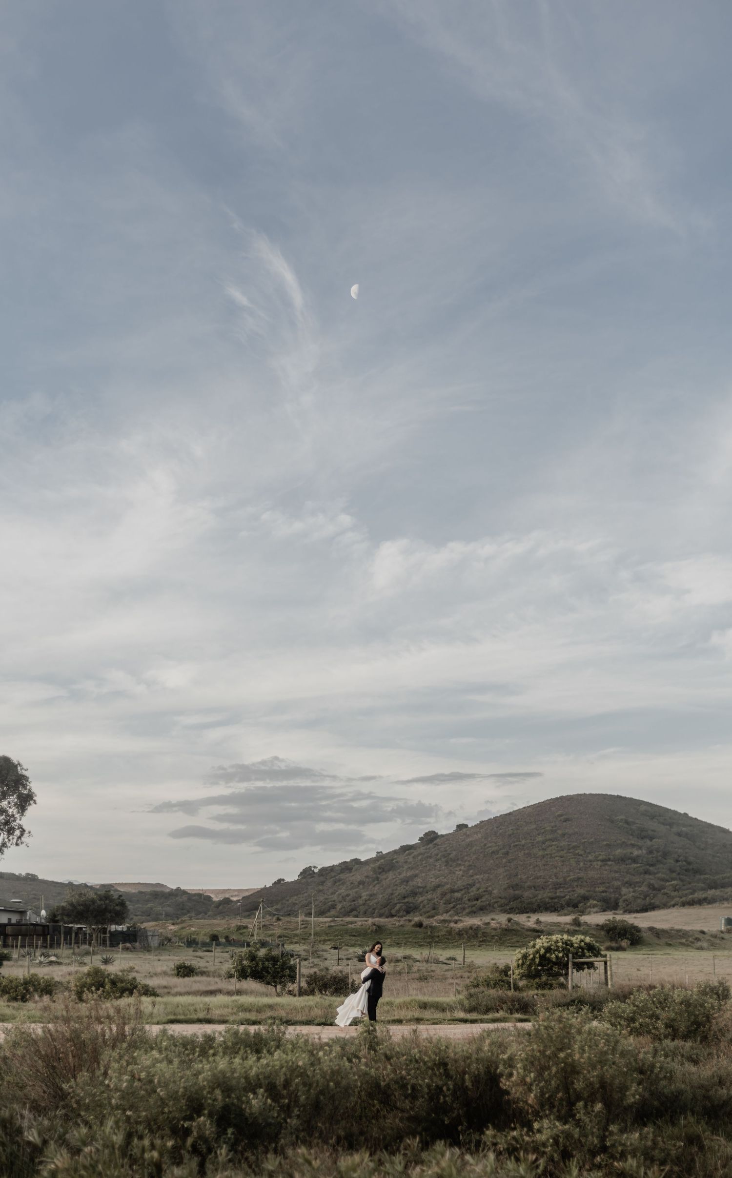 A panoramic view of rolling hills and grasslands under a cloudy sky at dusk in a serene rural landscape.