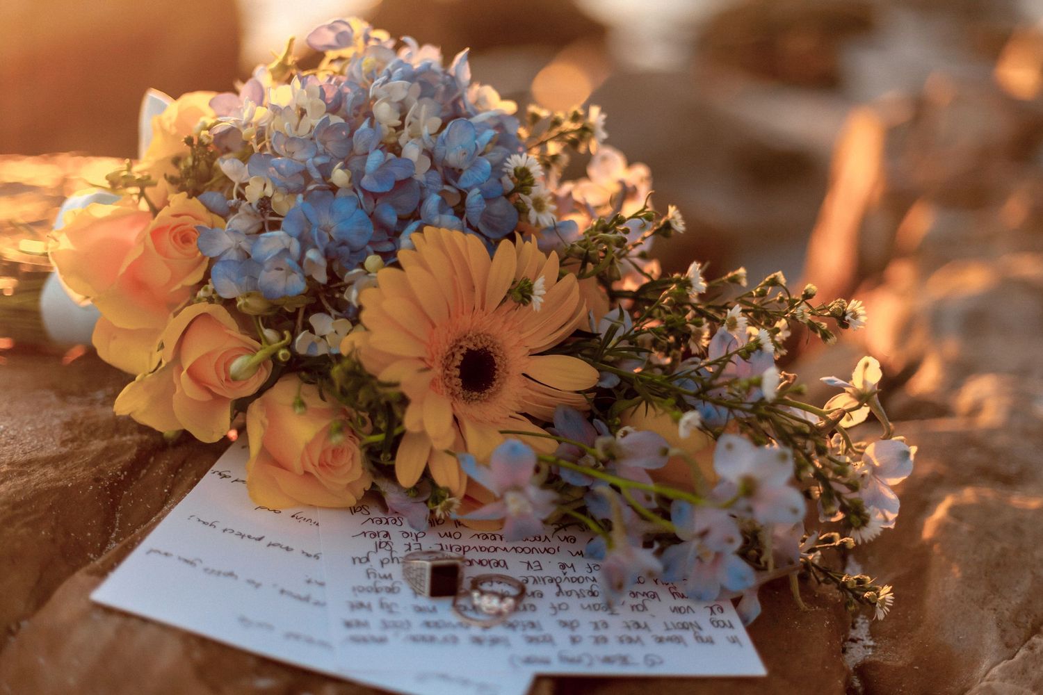 Handwritten wedding vows and delicate floral arrangements with peach and white flowers in warm sunset lighting.