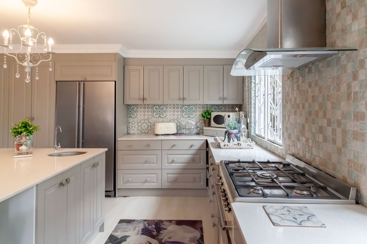 Modern white kitchen design featuring granite countertops, stainless steel appliances and elegant pendant lighting.