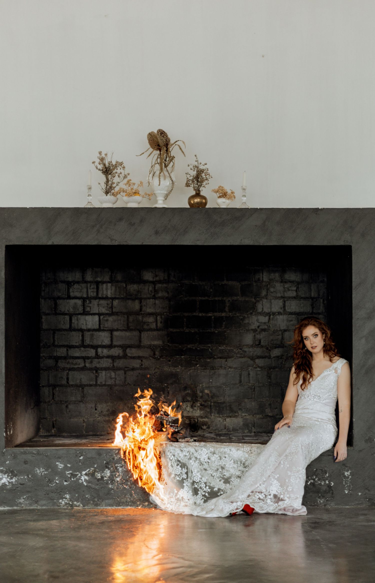 Series of photos showing a dramatic wedding dress burning sequence against a dark brick wall.