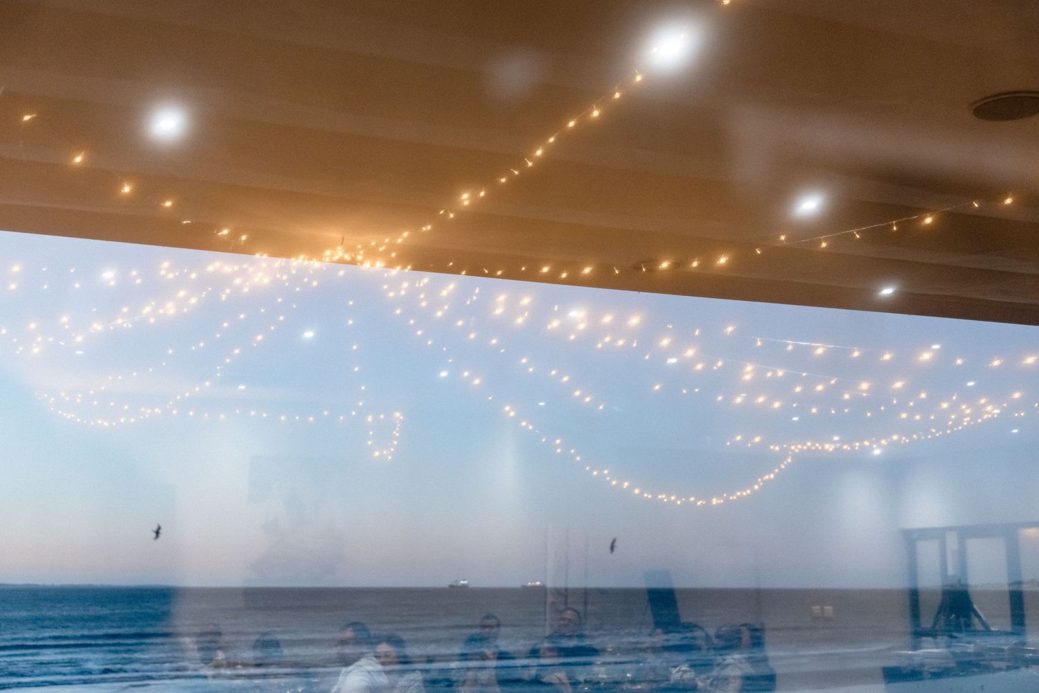 String lights illuminate a white ceiling creating a warm ambiance at an indoor event venue.