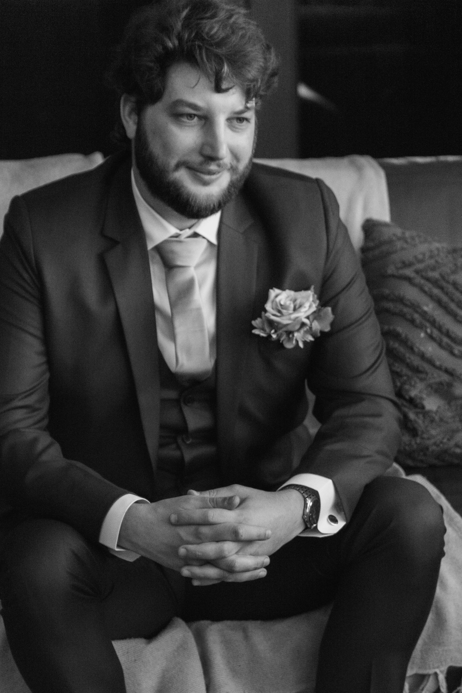 Black and white photo series showing a person in a formal suit with boutonniere looking down at their hands.