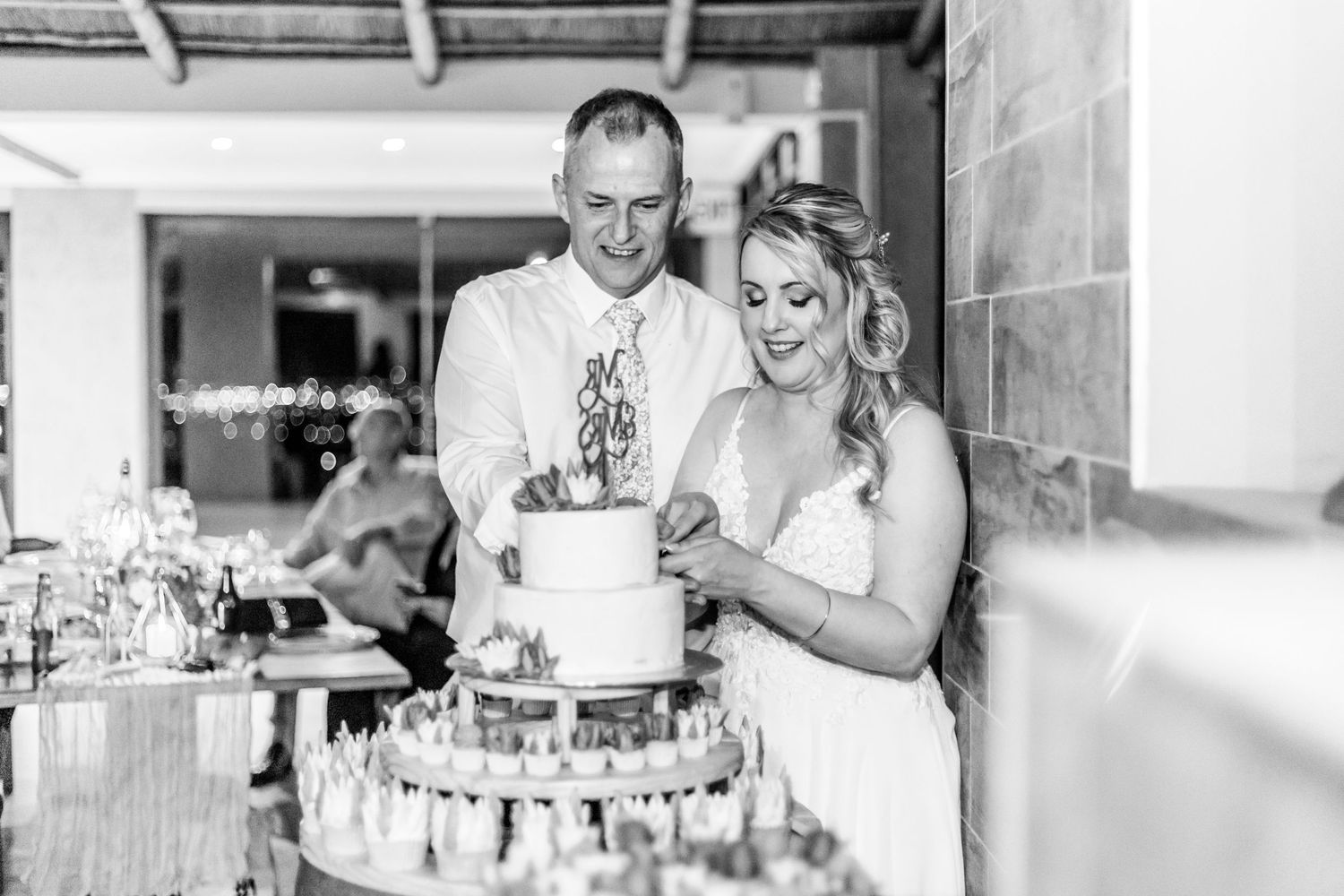 A romantic black and white photo collage showing several candid moments from a wedding celebration and cake cutting.