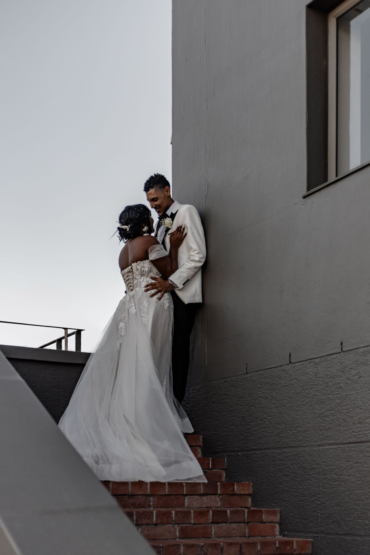 Black and white wedding photo series showing tender moments against a textured wall background.