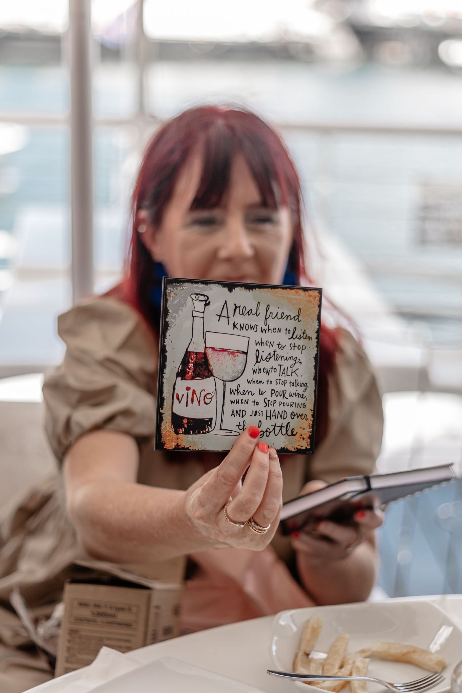 Someone holding up a decorative coaster featuring artwork of a wine bottle and Eiffel Tower design.
