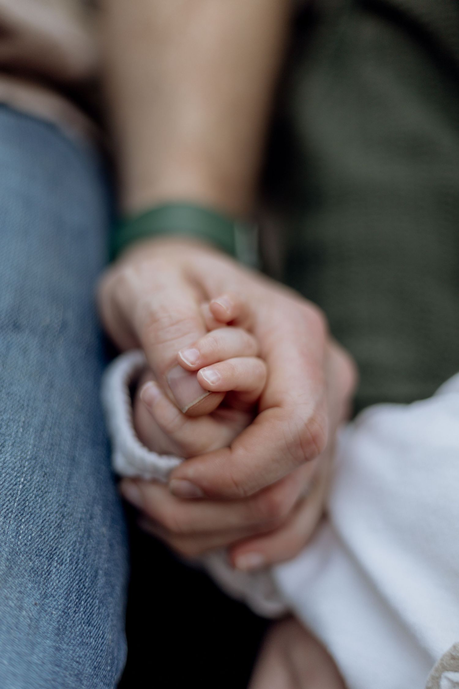 A sequence of close-up shots showing two hands holding each other in a caring gesture against a denim background.