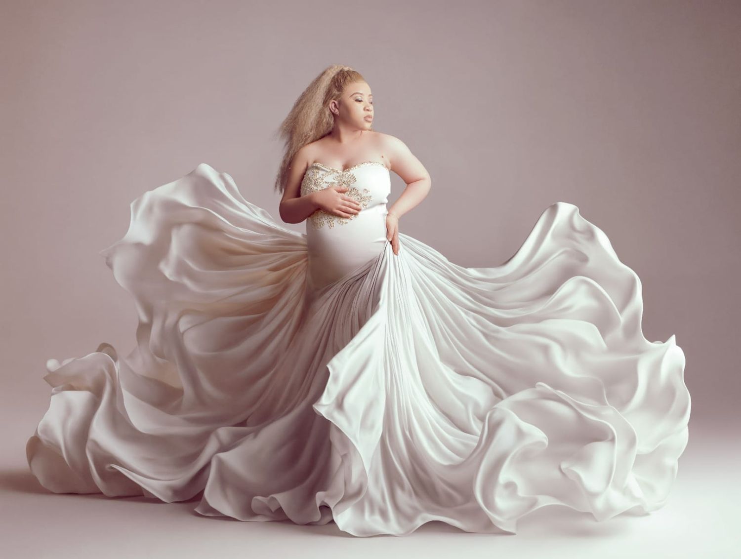 Flowing white dress fabric billowing dramatically across a soft pink backdrop.