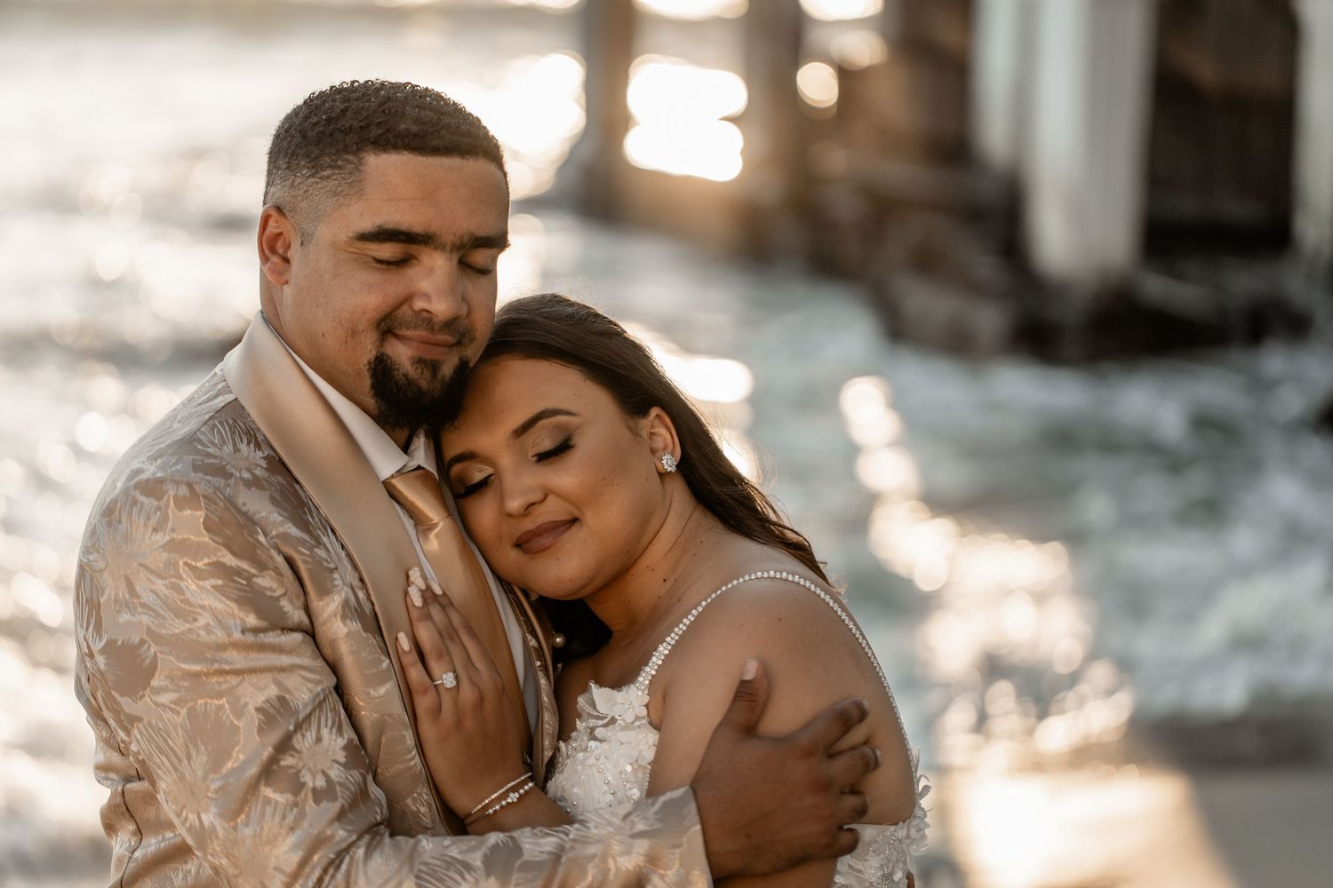 A romantic couple shares an intimate embrace during a golden hour photoshoot wearing formal attire.