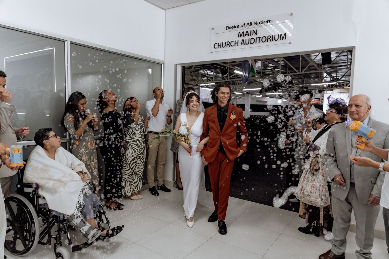 A group of people gathered indoors at what appears to be a celebratory event with streamers and confetti falling.