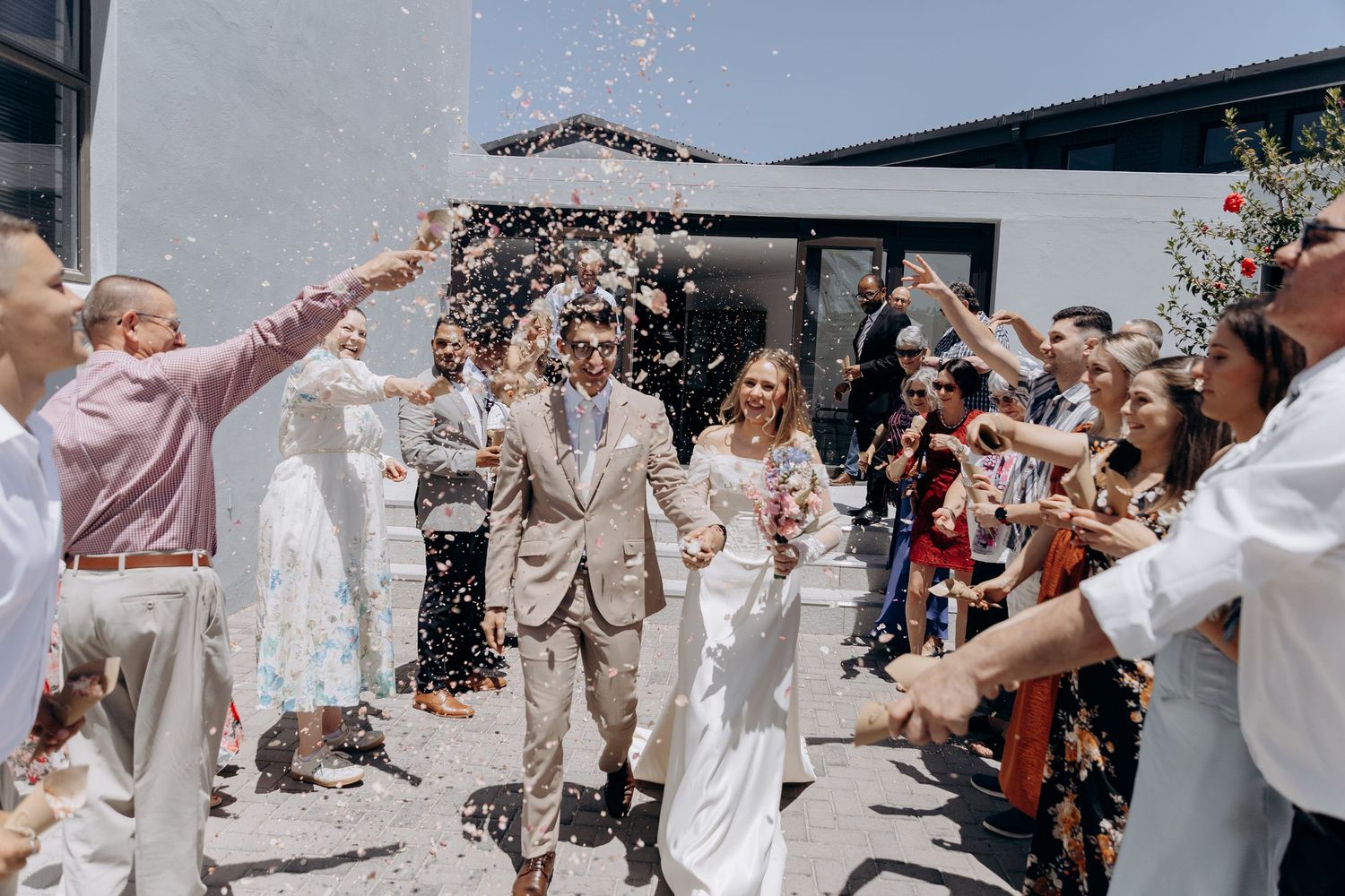 Wedding guests shower the happy couple with confetti as they exit the ceremony in a joyful celebration.
