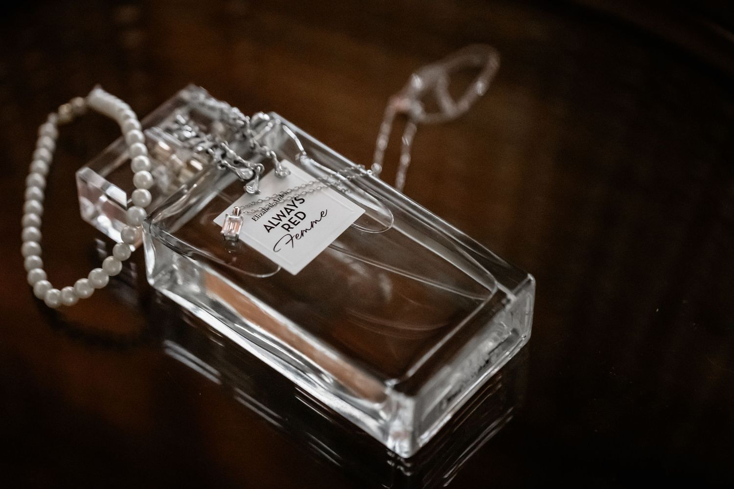 Elegant glass perfume bottles arranged artistically on a dark reflective surface with soft lighting.