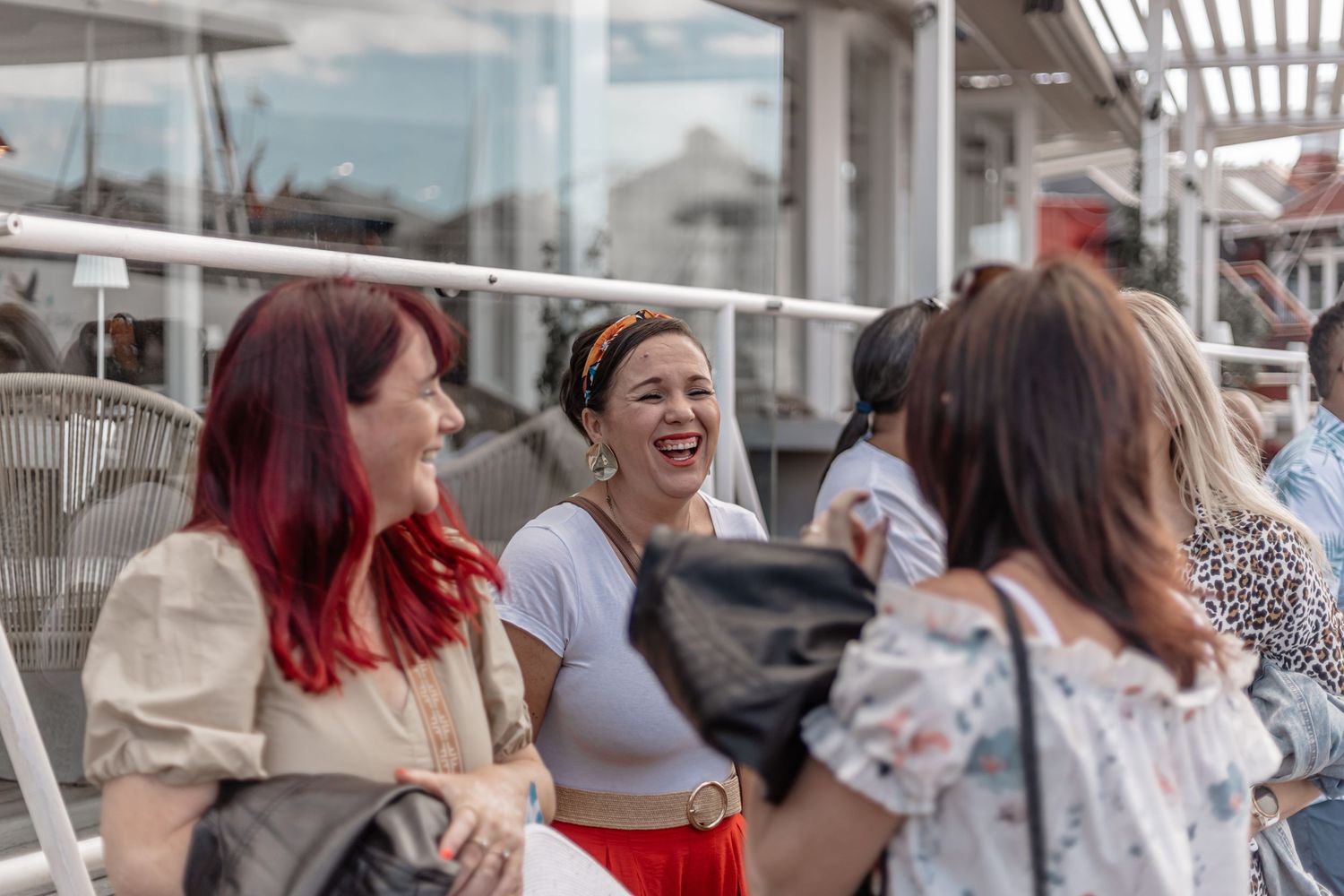 A group of friends share a joyful moment together while chatting on an outdoor patio or terrace.