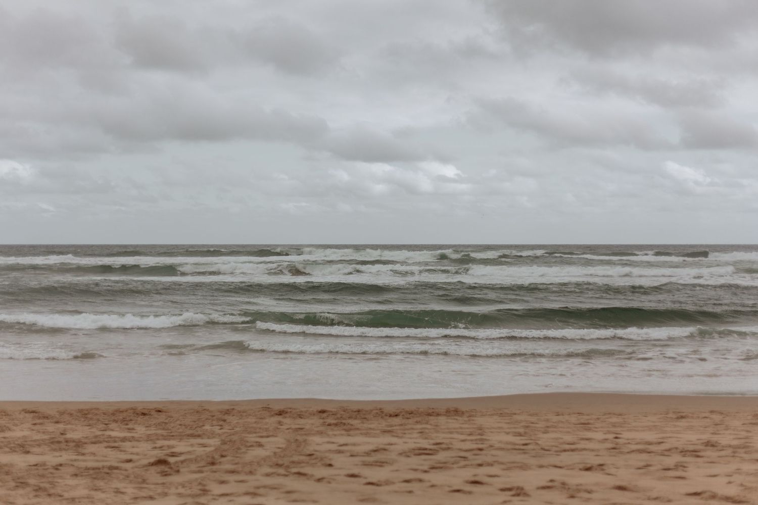 A series of stormy beach landscape photos showing rough seas and dark cloudy skies along a sandy coastline.