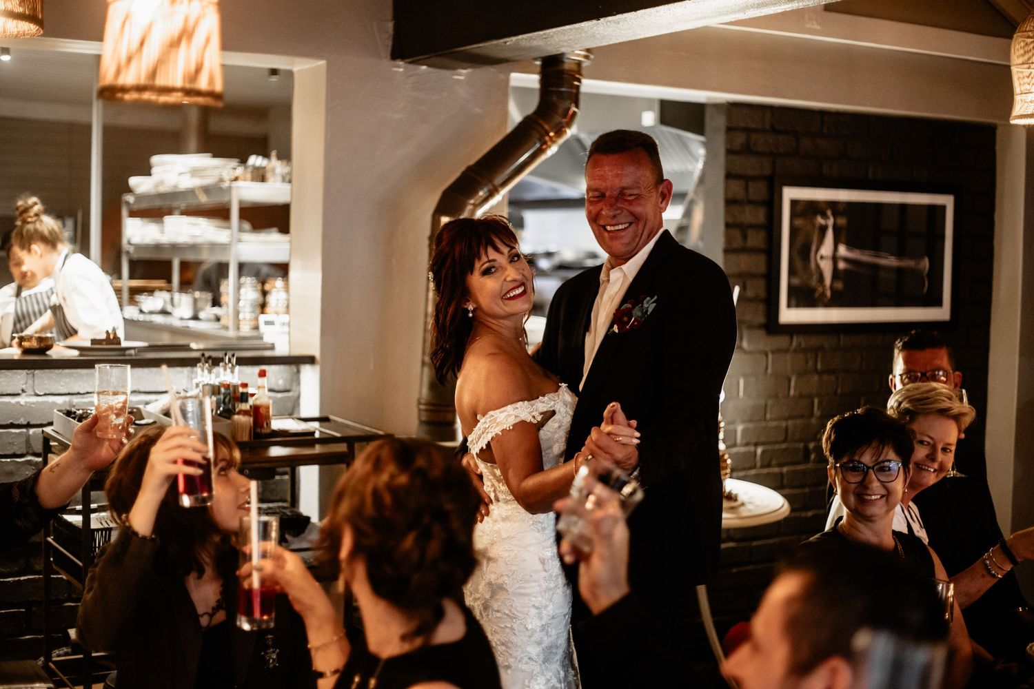 People celebrating at a wedding reception dance joyfully together in an intimate indoor venue.