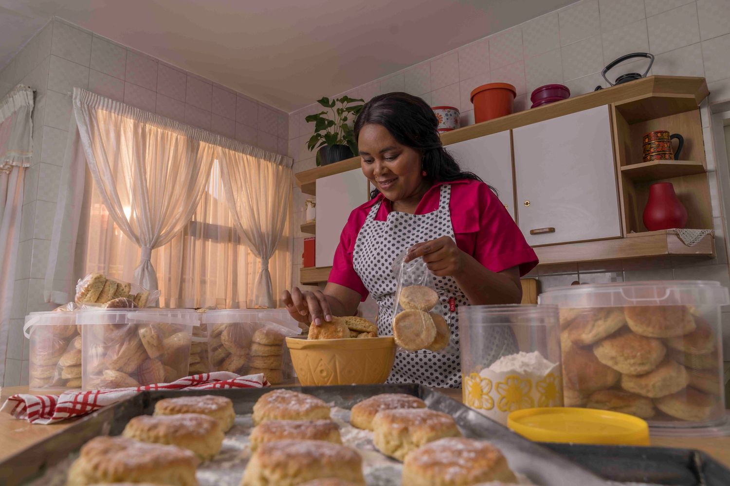 Baker in a pink sweater kneads and prepares fresh bread dough in a bright, organized home kitchen.