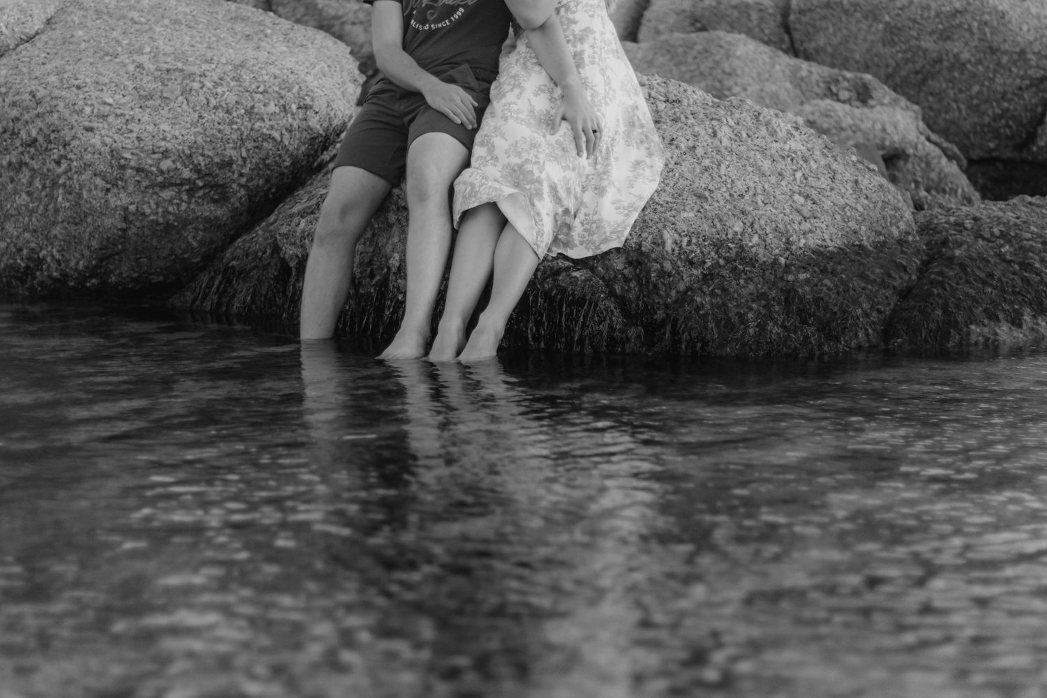 People sitting together by a serene stream with their feet in the water on a peaceful summer day.