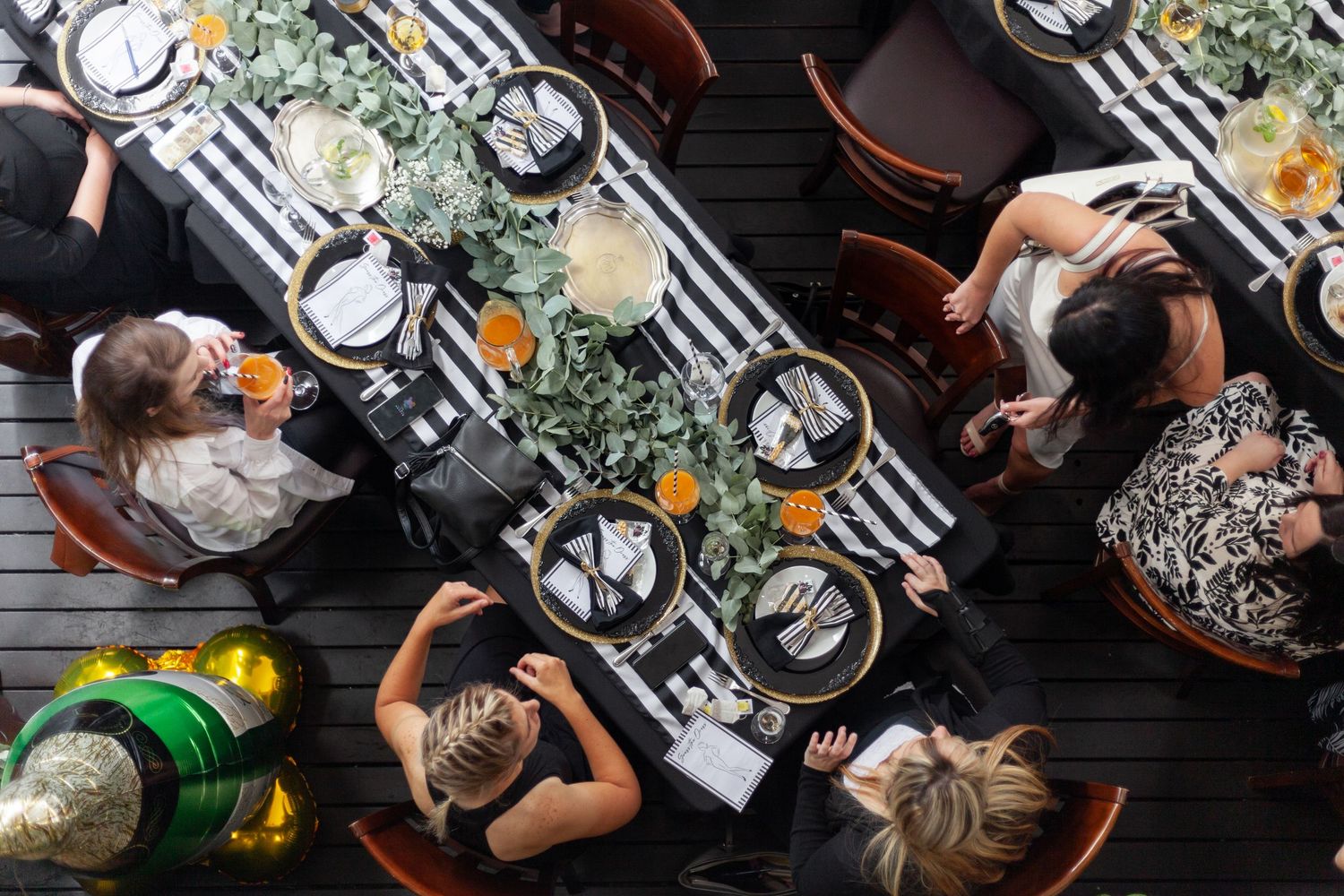 Overhead view of a dinner table with striped tablecloth, place settings, and greenery decorations.