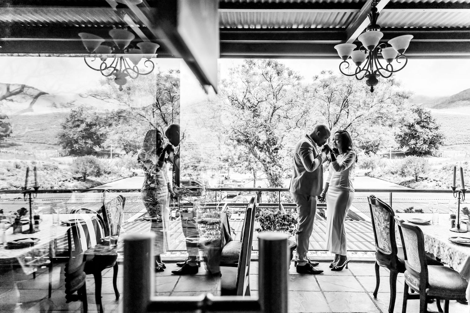 Black and white wedding photo captured at an elegant outdoor venue with rustic decor and mountain views in the background.