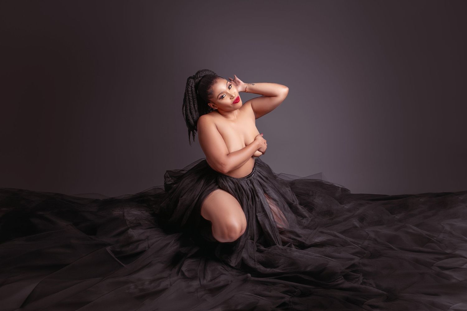 Artistic boudoir photography with flowing black tulle fabric against dark background creating dramatic contrast and mood.