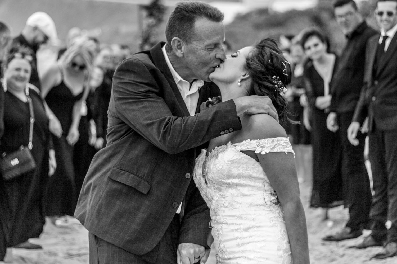 A black and white photo collage showing four romantic wedding kisses between couples at different celebrations.