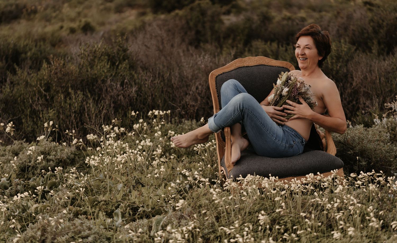 Woman in casual attire relaxes in a wildflower meadow during golden hour outdoor photography session.