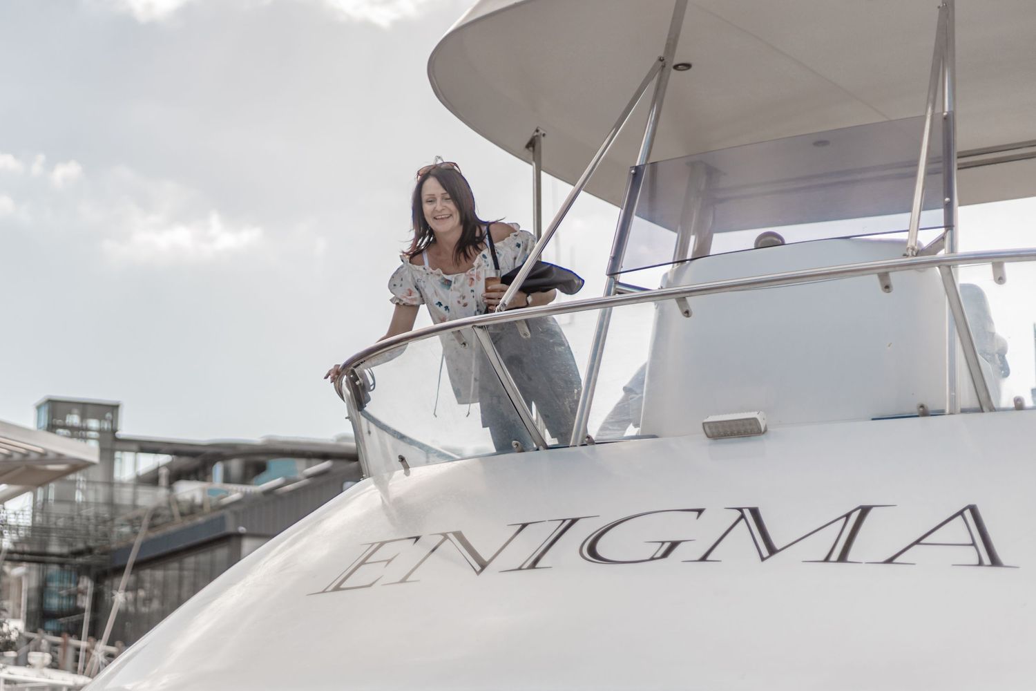 Looking up at a yacht crew member standing at the helm on a luxury vessel named Enigma.