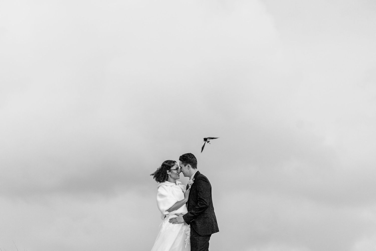 Bride and groom share an intimate moment while dancing outdoors in front of a scenic natural backdrop.