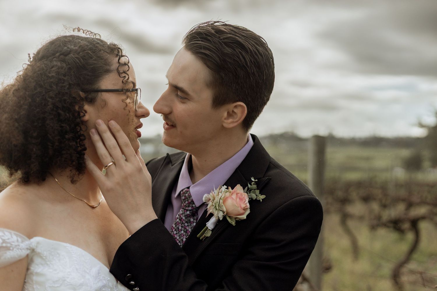 A loving couple embraces and kisses against a beautiful outdoor landscape.
