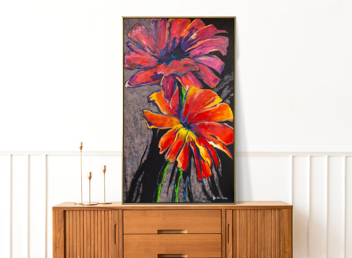 A vibrant floral art piece featuring red and orange tropical flowers mounted above a wooden credenza with candles.