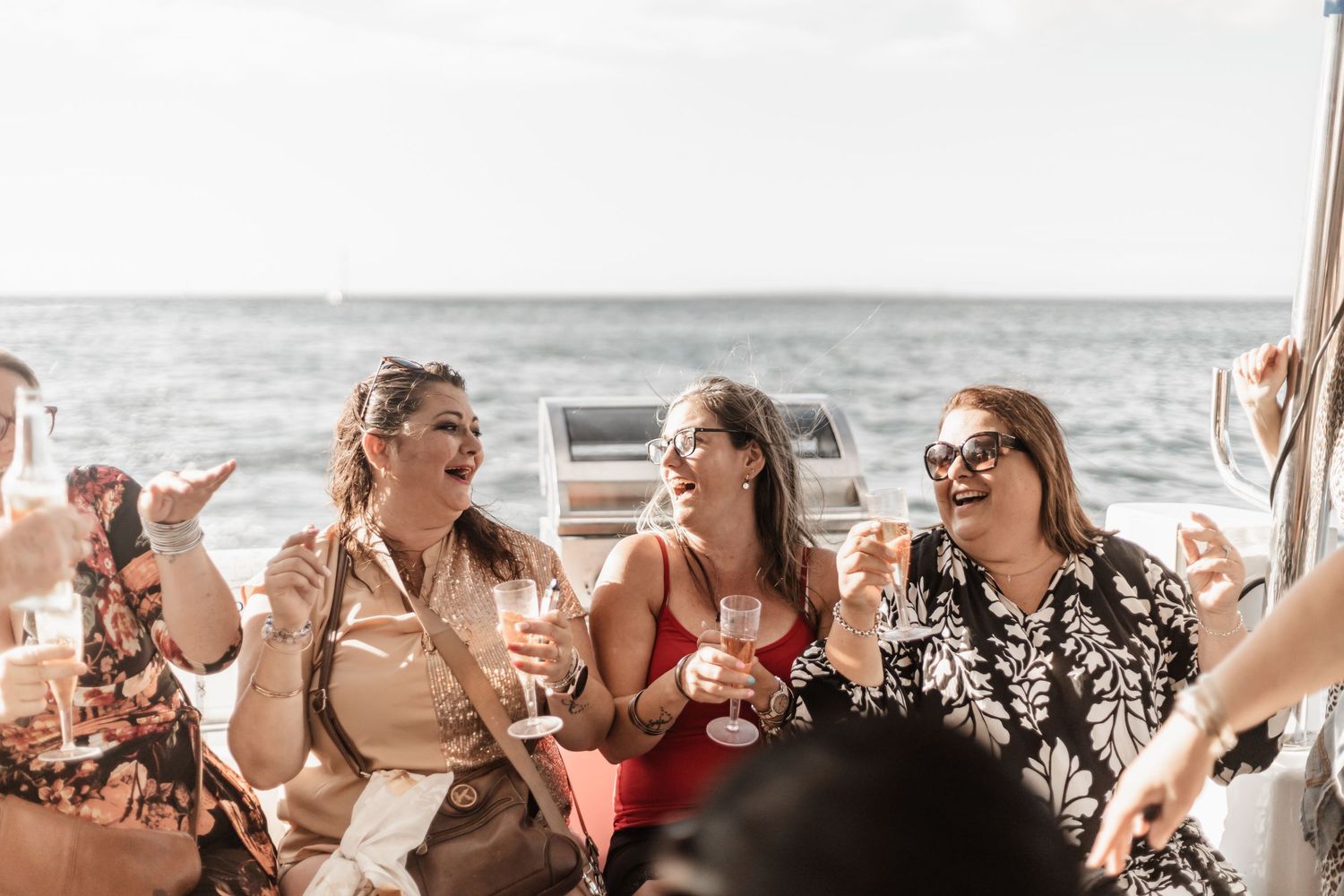 Friends enjoying drinks and conversation while sailing on a boat during a sunny afternoon.