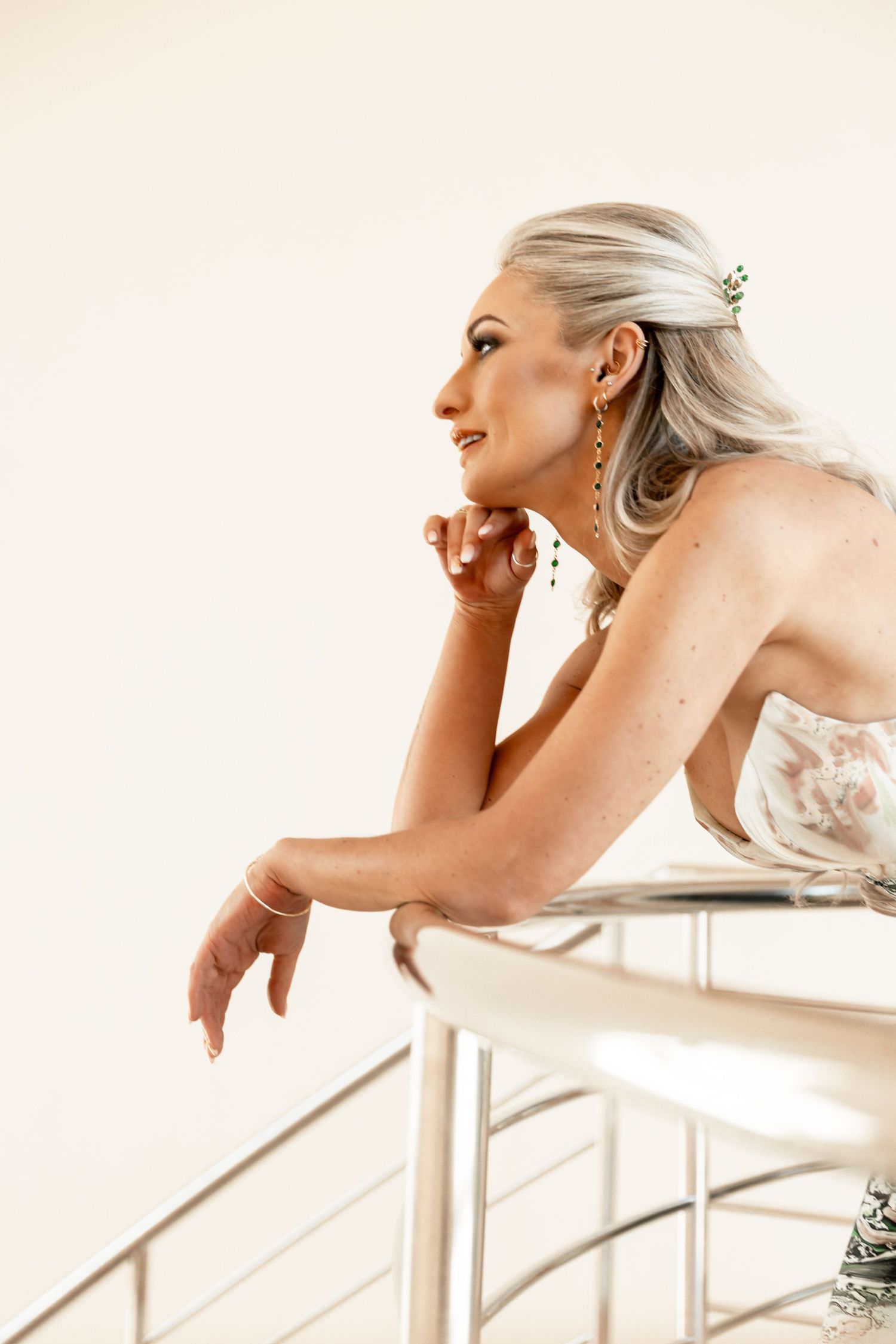 A bride in a white strapless dress with platinum hair leans thoughtfully against a modern railing.