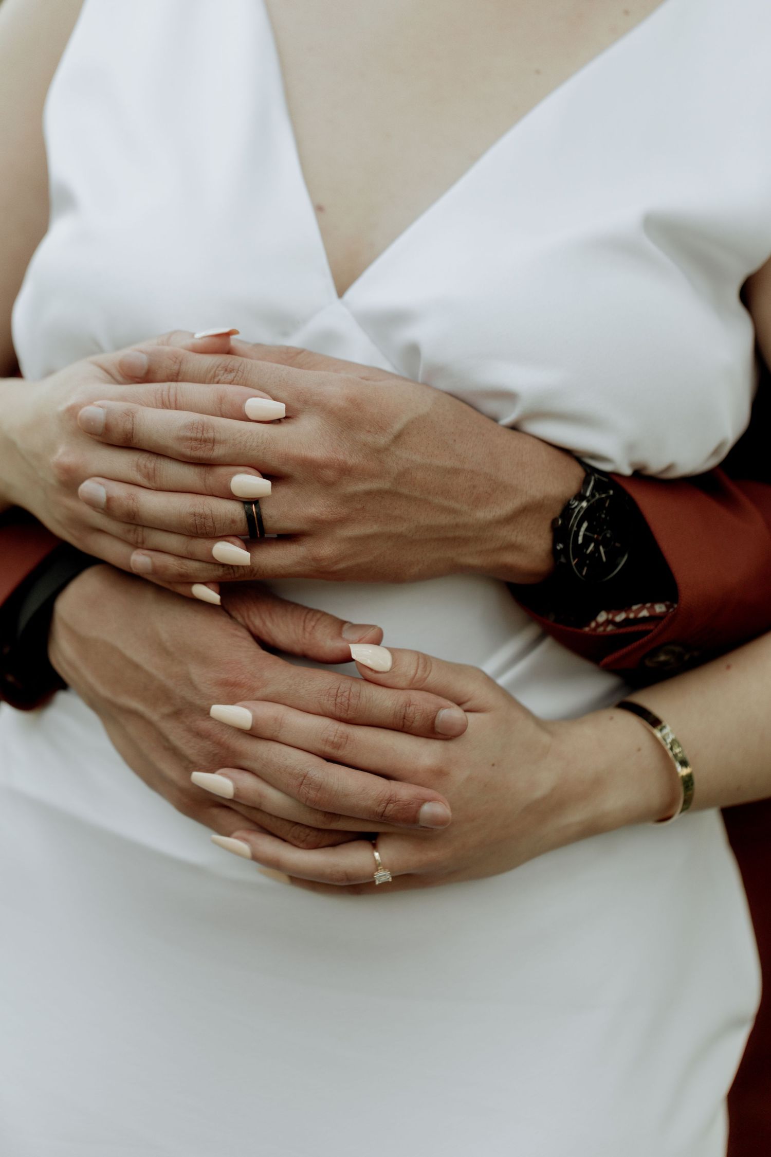 A series of intimately cropped photos showing two hands wearing wedding rings and white clothing.