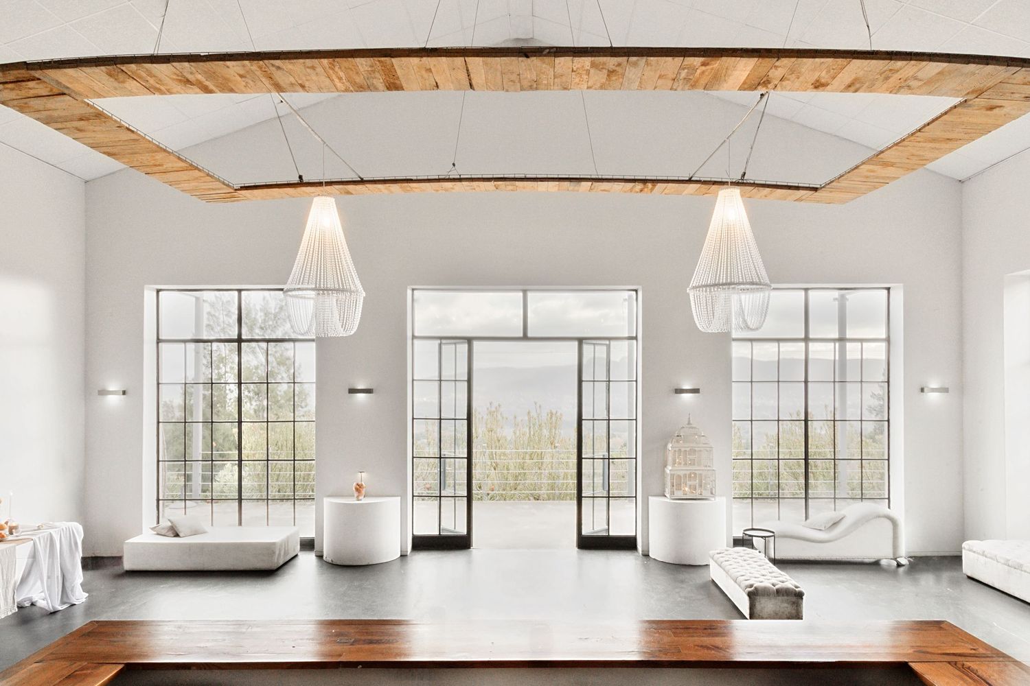 Bright modern loft space with white walls, exposed wooden beams, and large industrial windows letting in natural light.
