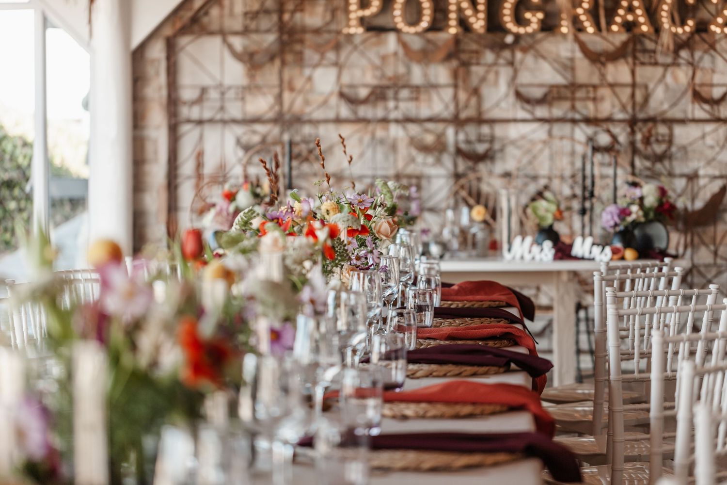 Elegant wedding reception venue with crystal chandeliers and white chairs arranged under a rustic wooden ceiling.