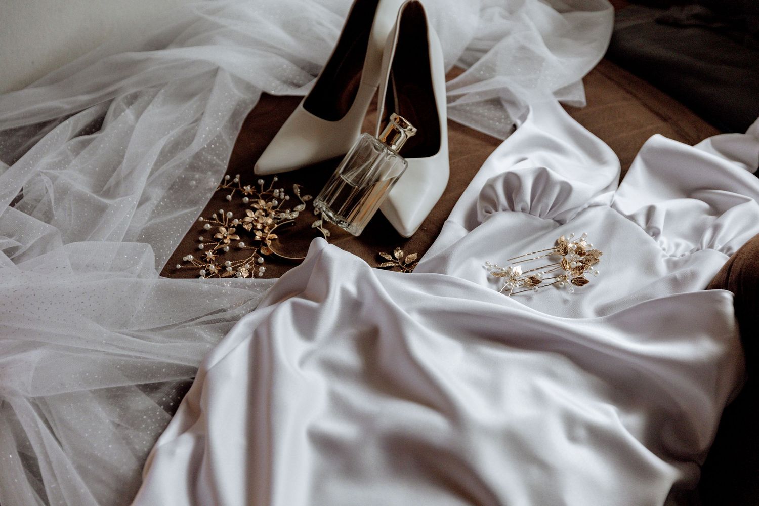 A delicate spread of white wedding dress tulle fabric with elegant bridal accessories arranged on top.